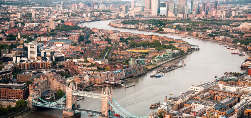 A photo of London takes from a helicopter showing the Thames river, London Bridge and several sky scrapers.